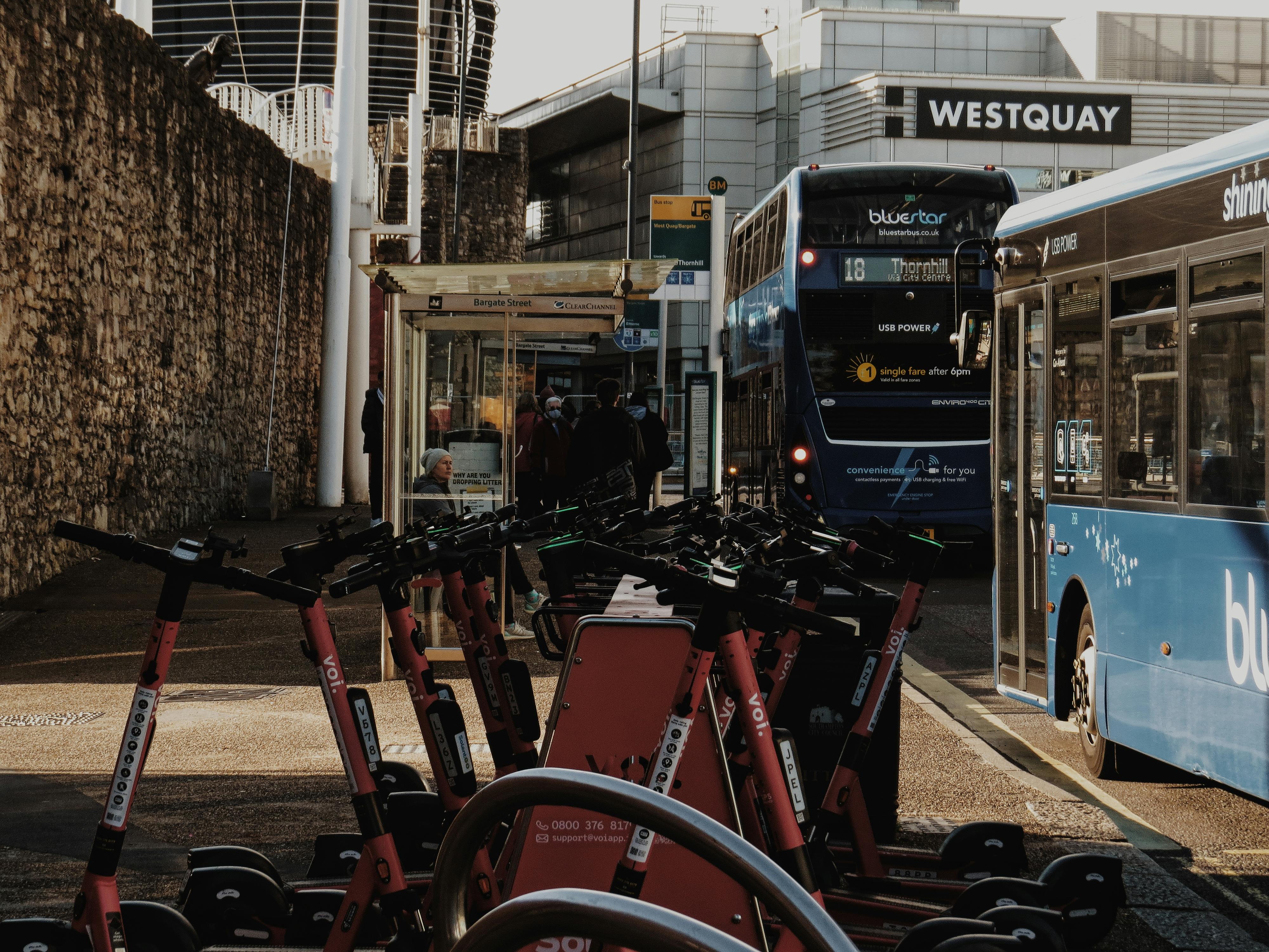 Red bikes parked at a public transport hub with buses in the background