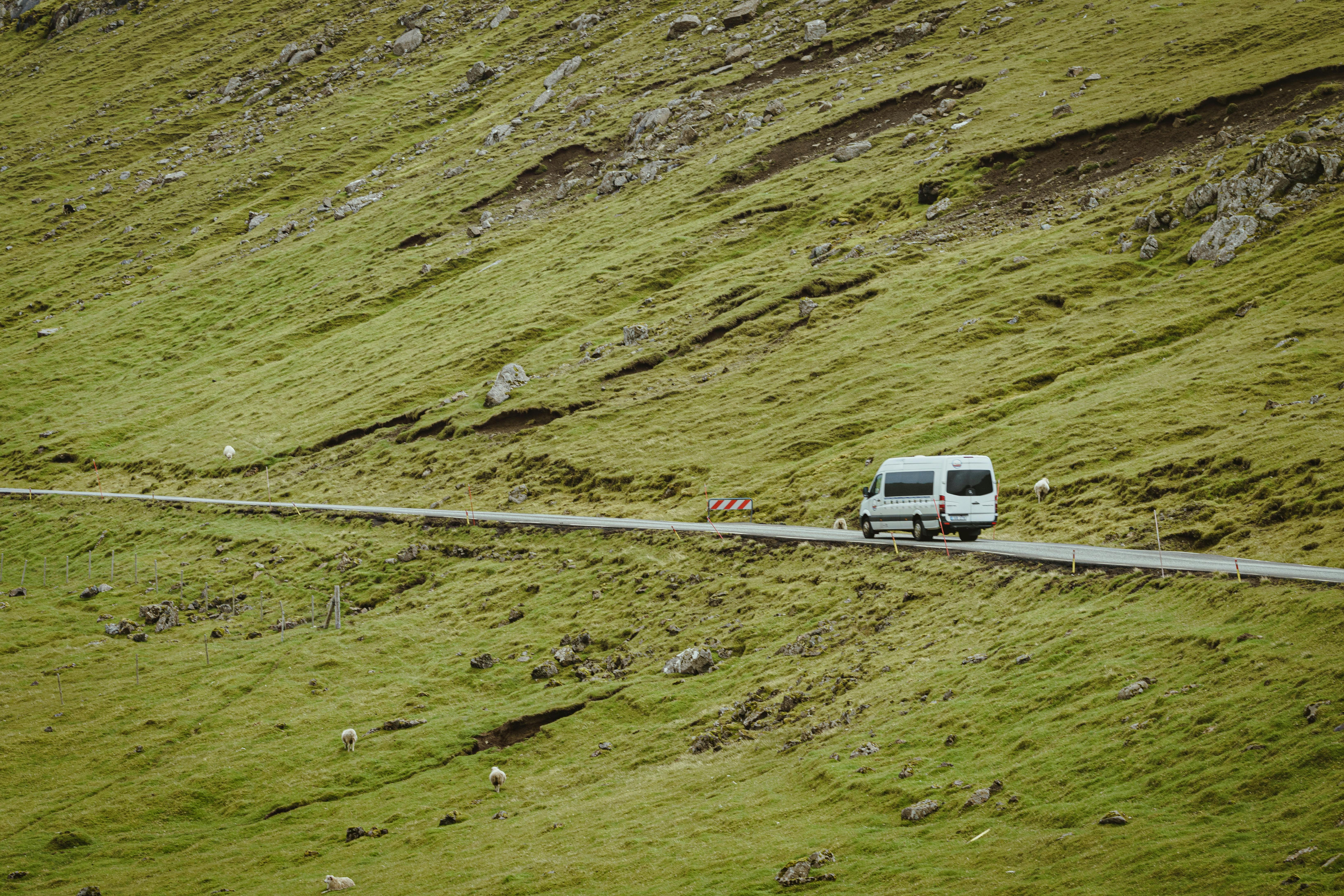 White van traveling on a scenic mountain road through green hillside landscape